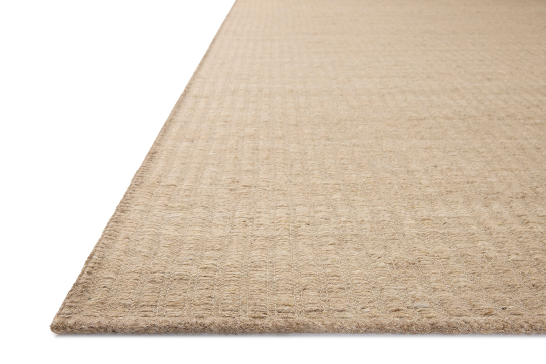Close-up of a Natural Elm wool area rug corner on a white background