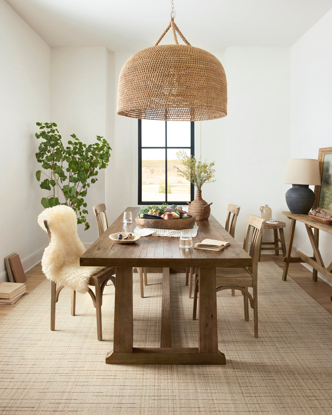 Dining room with wooden table, chairs, and decorative elements. Brooks wool beige area rug on the floor