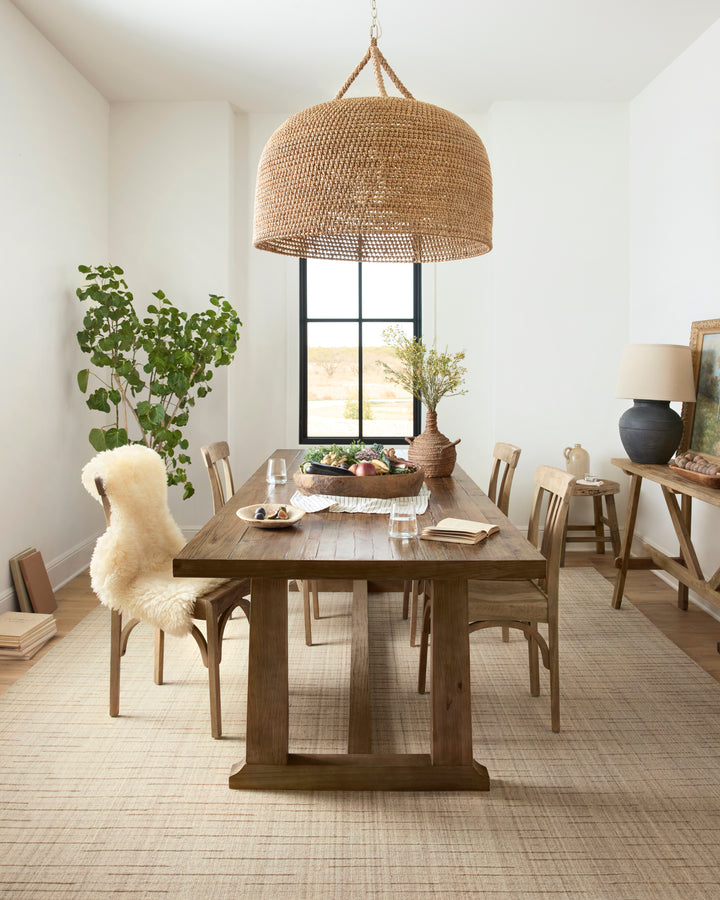 Dining room with wooden table, chairs, and decorative elements. Brooks wool beige area rug on the floor