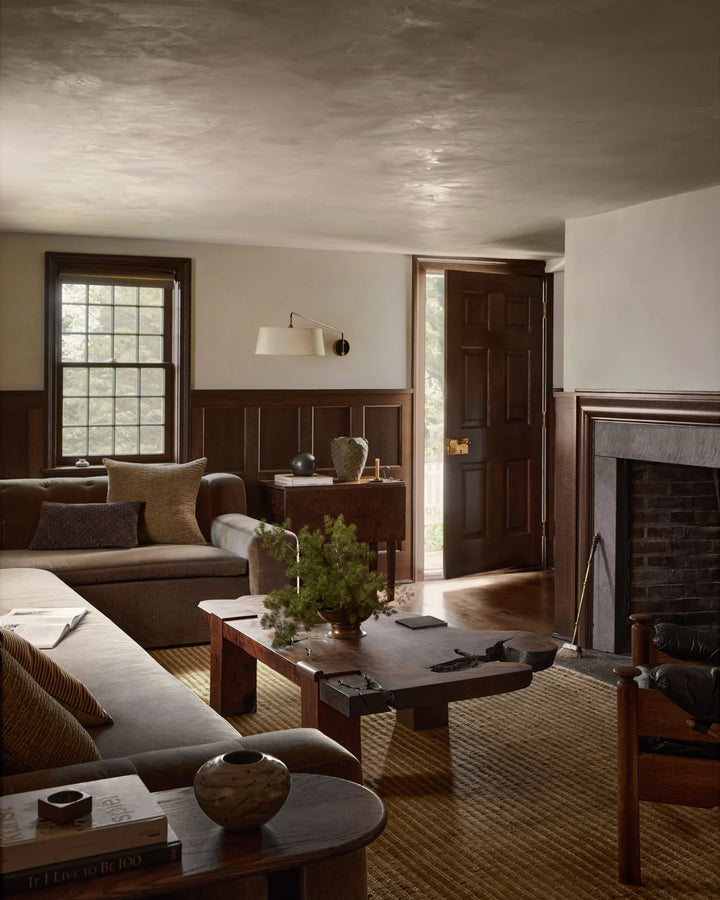 Cozy living room with a fireplace, couch, and coffee table. Elm warm beige area rug on wood floor