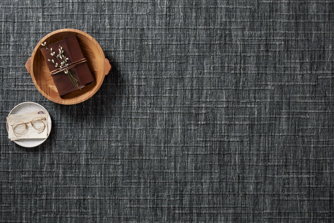 Textured Ink blue area rug with a small wooden bowl containing a chocolate bar and a white dish with glasses.