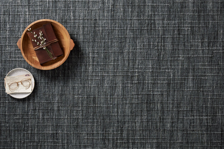Textured Ink blue area rug with a small wooden bowl containing a chocolate bar and a white dish with glasses.
