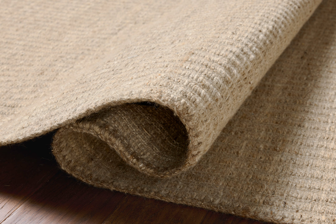 Rolled-up beige textured rug on a wooden floor