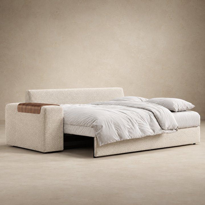 Vilander Sofa Bed with Wide Arms in 357 Off White Boucle textured upholstery, featuring walnut wood armrest accents and a modern design, shown against a warm beige studio background.