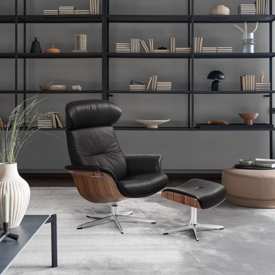 Modern TimeOut by Conform black leather armchair with wooden accents in a stylish room with shelves and decor.